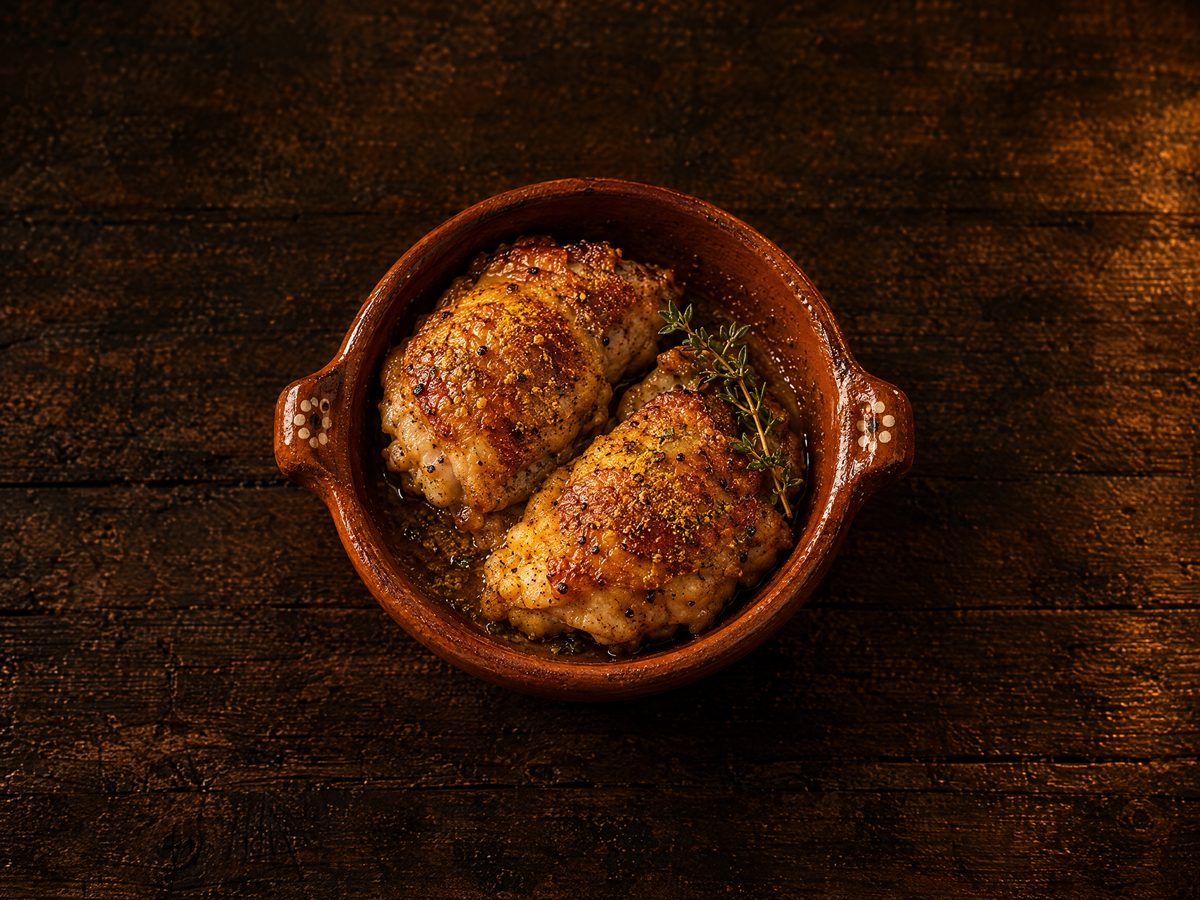 Dos piezas de pollo doradas en cazuela de barro